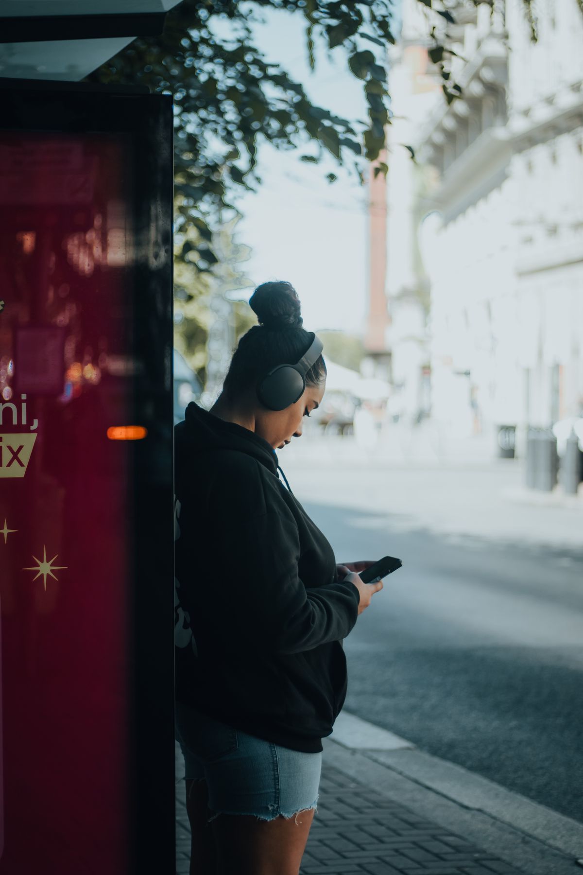 Woman checking her phone while waiting at a transit stop
